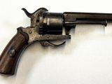 un vieux revolver avec une poignée en bois sur une surface blanche