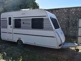 une petite caravane blanche garée dans un jardin