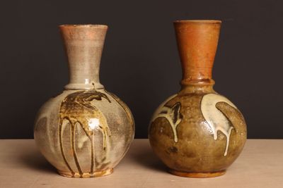 deux vases posés sur une table, sur fond noir