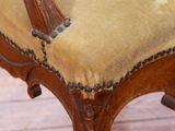 a wooden chair with a tan upholstered seat on a hard wood floor