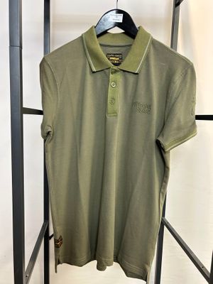 un polo vert suspendu à un portant dans une pièce