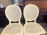 une paire de chaises à dossier en osier blanc posées sur un tapis rouge dans une pièce