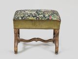 a green upholstered foot stool with a floral upholstered seat