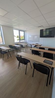 des tables et des chaises dans une salle de classe, avec un téléviseur à écran plat accroché au mur