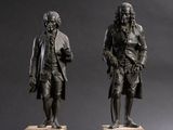 two bronze statues of men standing on marble bases
