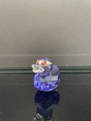 un canard en verre violet posé sur une table noire