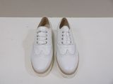 pair of white leather shoes with laces on a white surface