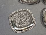 six silver plate coasters on a table with a red box in the background
