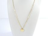 a gold necklace with a heart charm on a mannequin neck