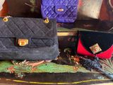 three purses sitting on top of a table next to a pile of luggage