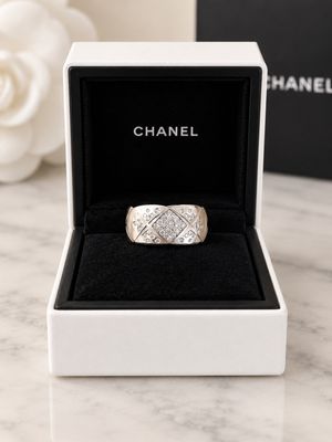 a close up of a ring in a box with a rose in the background
