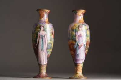 pair of vases with painted figures on them sitting on a table