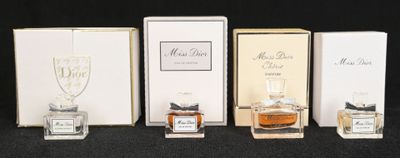 Quatre flacons de parfum sont alignés sur une surface noire