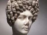marble head of a woman with curly hair on a pedestal