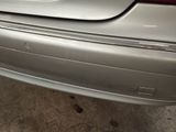 the rear end of a silver car with a broken bumper