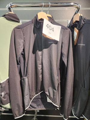 trois vestes suspendues à un portant dans un magasin, avec leurs étiquettes de prix