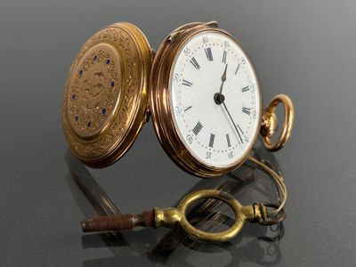 a gold pocket watch sitting on a table with a key