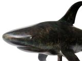 a bronze shark statue on a stand on a white background