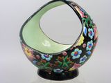 black and green vase with flowers on it on a clear base