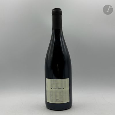 une bouteille de vin posée sur une table à côté d'un mur blanc