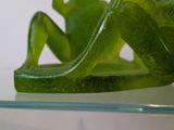 a green frog sitting on top of a glass shelf