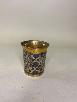 une tasse dorée et noire ornée d'un motif représentant des oiseaux