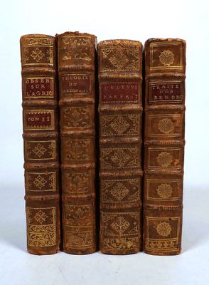 four old books are lined up in a row on a white surface