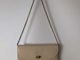 beige leather purse hanging on a hook on a white wall