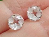 une paire de boucles d'oreilles à clous en topaze blanche et diamants au doigt d'une personne