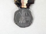 a silver medal with a ribbon around it on a white surface