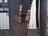 a close up of a rusted metal pole with a sign in the background