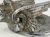 a silver statue of a winged animal on a white surface