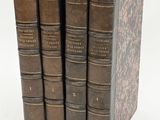 three old books are stacked on top of each other on a white surface