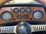 dashboard of a classic car with a wooden steering wheel and gauges