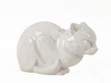 a white cat figurine sitting on a white surface
