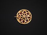 a gold broochle with garnets on a black background