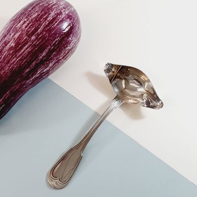 an eggplant next to a spoon on a blue and white surface