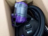 a purple and black vacuum in a box on the floor