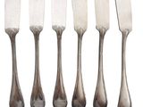 a set of six silverplated knives on a white background