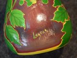 a green and yellow vase with leaves painted on it
