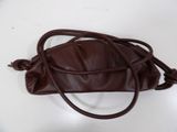 brown leather handbag on white table with strap around it