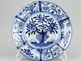 blue and white plate with a vase of flowers on it