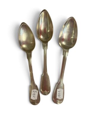 three silver spoons sitting next to each other on a white surface