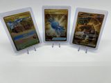 Trois cartes à collectionner Pokémon sont exposées sur une surface blanche