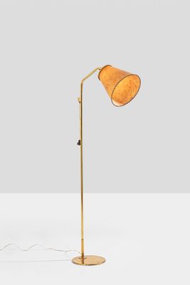 a gold floor lamp on a white surface with a white background