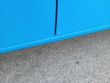 a cat that is standing on the floor near a blue cabinet
