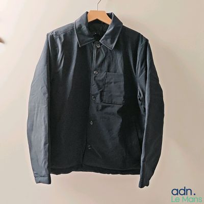 the jacket is hanging on a hanger in the corner of the room