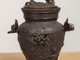 a small bronze vase with a bird on top of it
