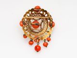 a close up of a broochle with red beads on a white surface