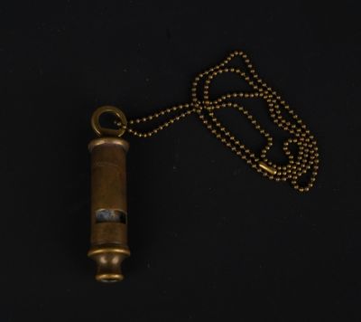 une vieille balle en laiton attachée à une chaîne sur fond noir